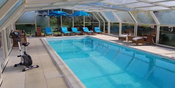 retractable pool enclosure covering indoor swimming pool with aluminum frame and polycarbonate roof