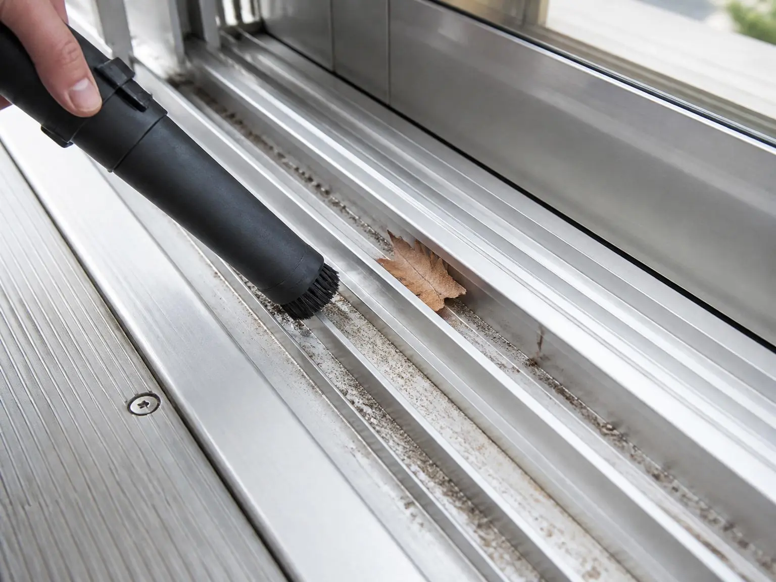 Cleaning debris and dust from the aluminum sliding track of a retractable sunroom