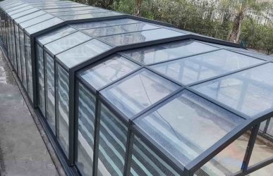 Glass pool enclosure with curved roof structure for an outdoor private pool