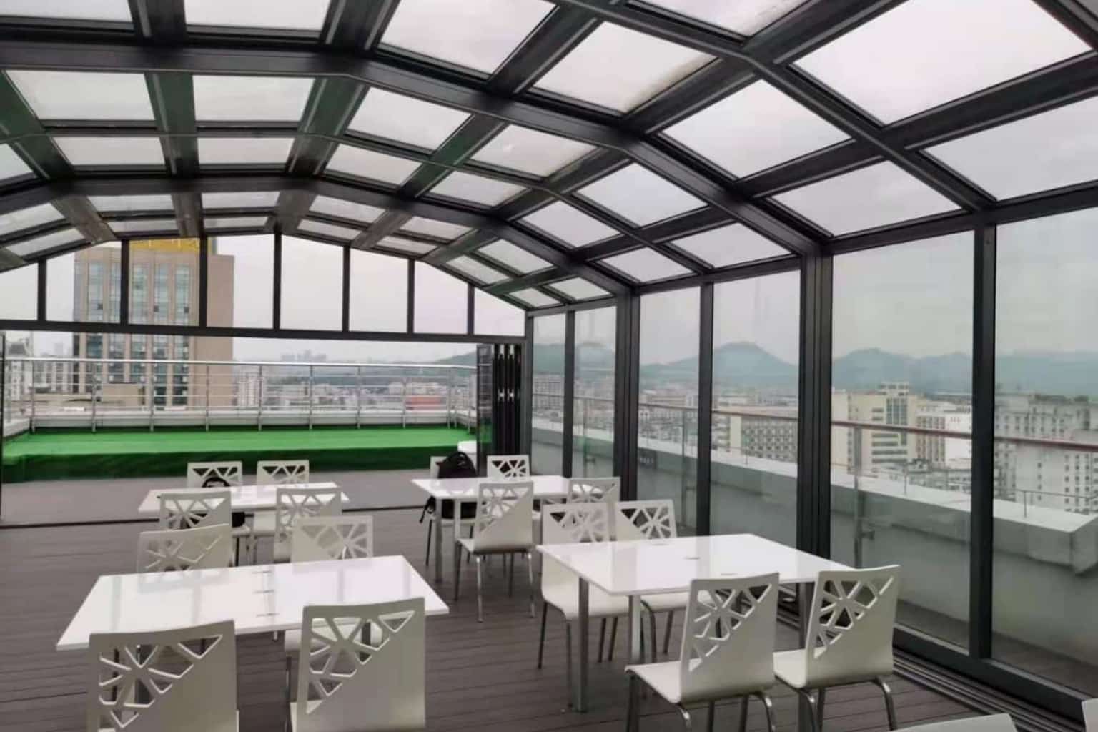 Motorized retractable roof system installed over a rooftop terrace with glass panels