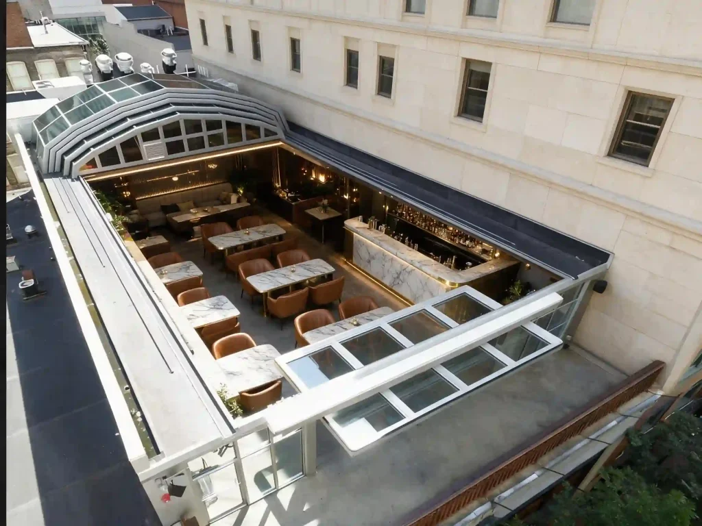 Hotel courtyard retractable glass roof system covering an outdoor dining area