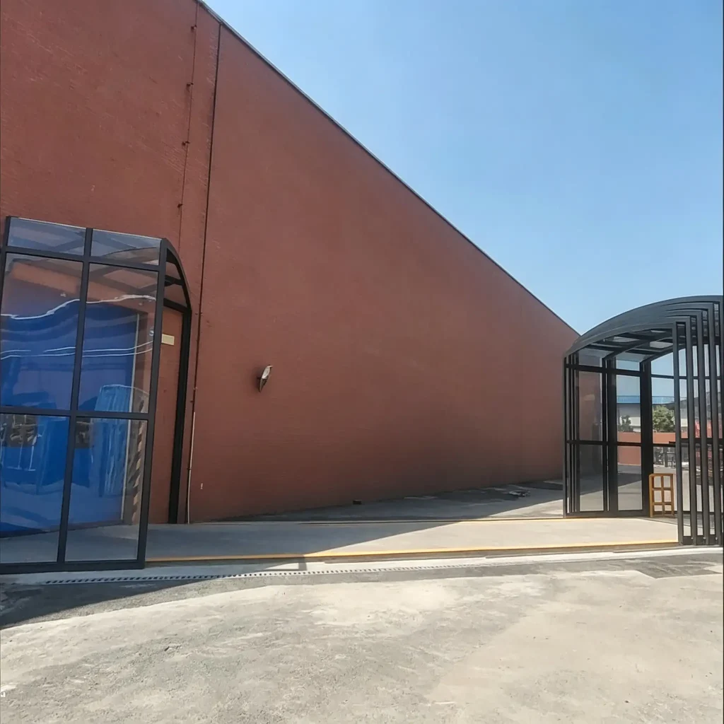 Industrial retractable walkway system installed along factory wall for protected outdoor passage